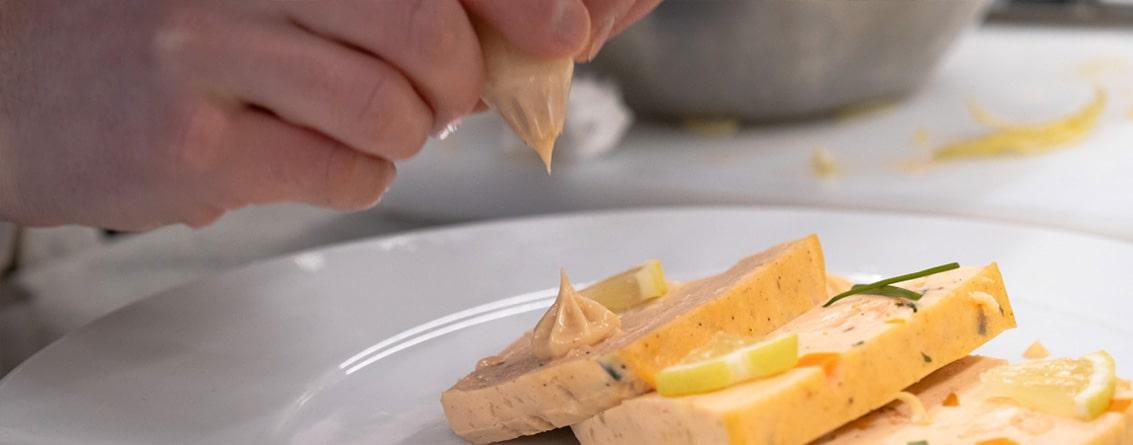 Gros plan sur un plat avec main qui dépose une noix de crème au pochoir