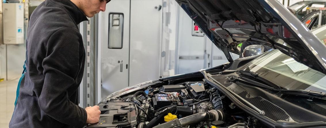Apprenti inspectant le moteur d'une voiture